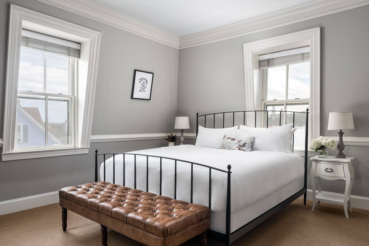 A bedroom with a large bed, a bench, two bedside tables, and a window with a view.