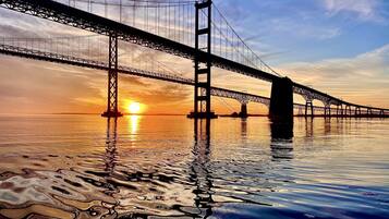 Een grote hangbrug boven kalm water tijdens de zonsondergang.