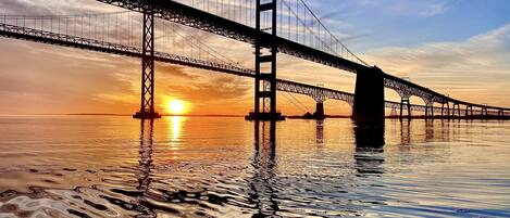 A large suspension bridge over calm water during sunset.