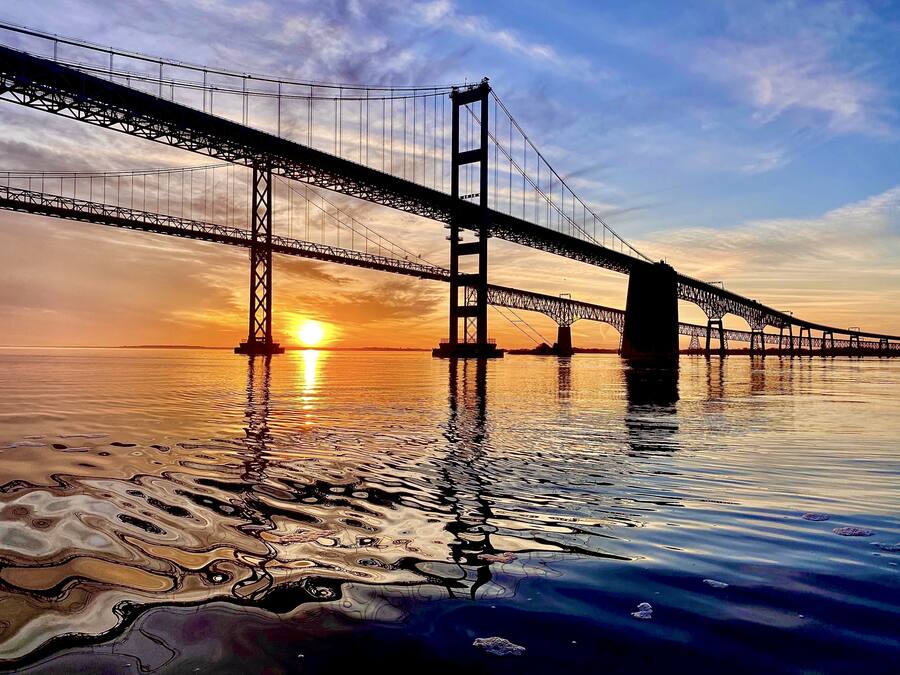 Een grote hangbrug boven kalm water tijdens de zonsondergang.