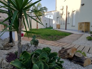 A courtyard with a wooden deck, a palm tree, and various cacti. - B&b Villa Kairos (Ioppolo Giancaxio)