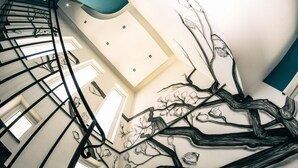 A spiral staircase with a wall mural of abstract tree branches. - B&b Villa Kairos (Ioppolo Giancaxio)