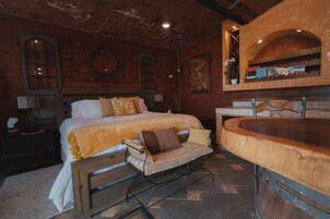 Um quarto acolhedor com uma cama grande, um banco, uma mesa de madeira e uma estante de livros.