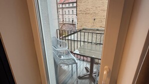 A balcony with a table and chairs, a view of buildings, and a door. - Urban Flame Apartments (Sarajevo)