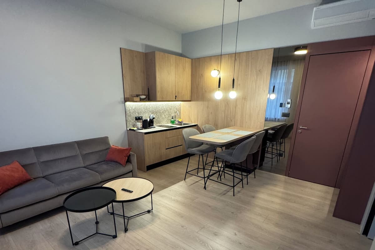 Una sala de estar moderna con un sofá, una mesa de centro y un reposapiés rojo.
