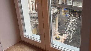 A view from a window with a wooden ledge, overlooking a street with buildings and a sculpture. - Urban Flame Apartments (Sarajevo)