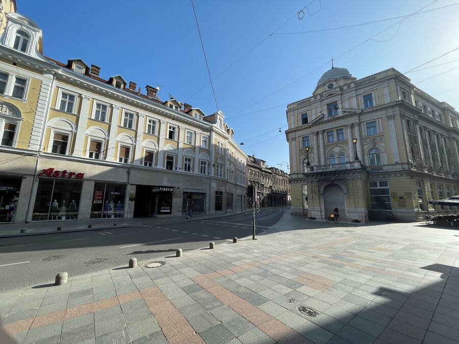 A wide pedestrian area with historic buildings, including a prominent building with a dome and another with a sign reading "Astra".