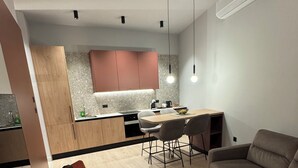 A modern living room with a sofa, a red chair, a glass coffee table, and a dining area with a table and chairs. - Urban Flame Apartments (Sarajevo)