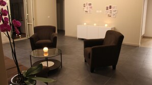 A modern living room with two brown armchairs, a glass coffee table, and a potted orchid.