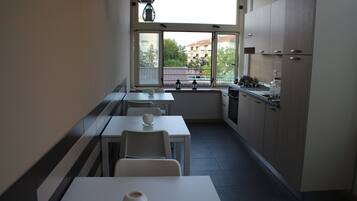 Eine moderne Küche mit Essbereich, großen Fenstern und Blick auf Gebäude.