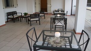 A spacious indoor area with multiple tables and chairs, a glass table with a decorative centerpiece, and a bench with a potted plant.