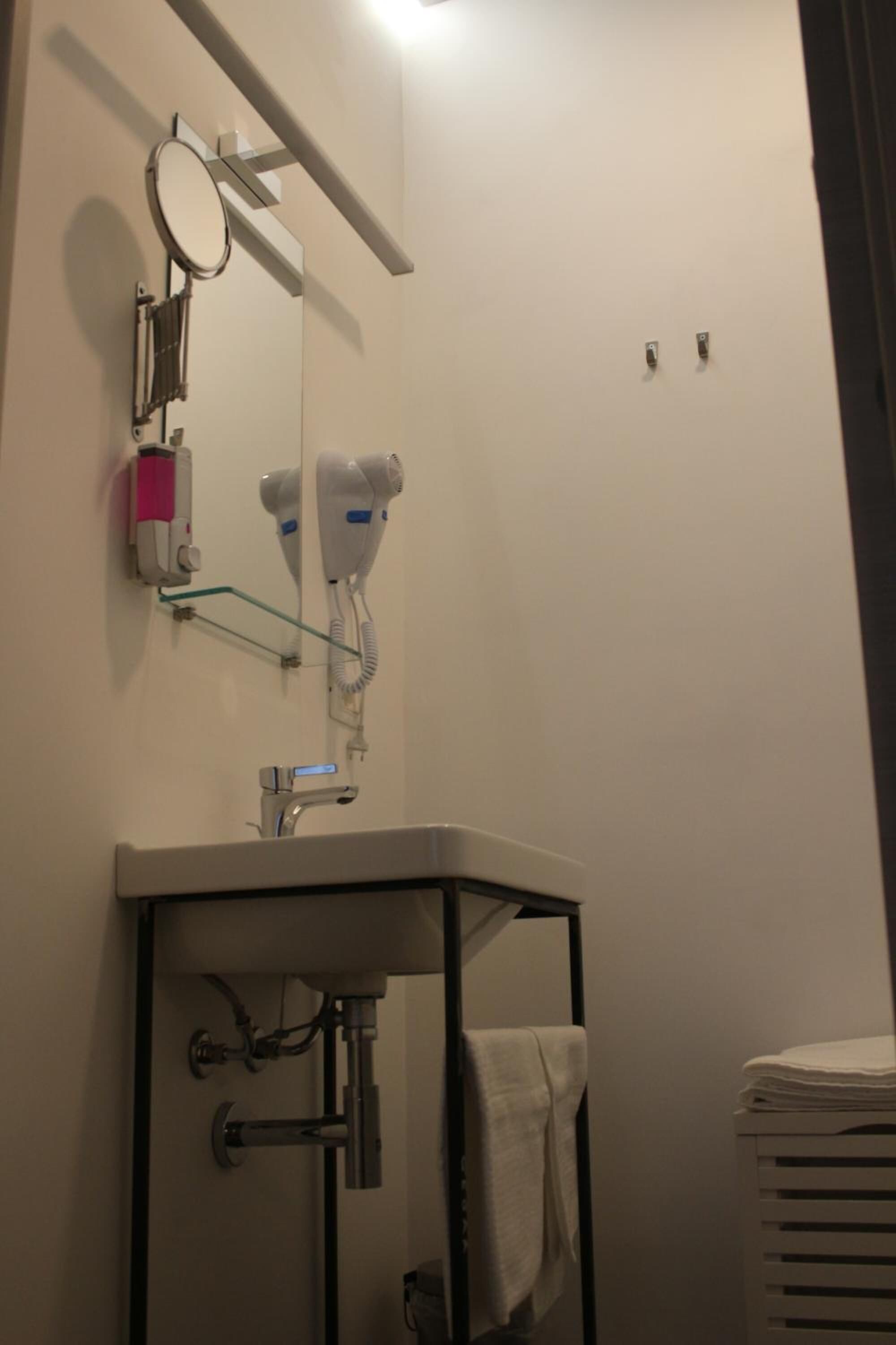 Un baño con lavamanos, espejo, secador de pelo y toallero.