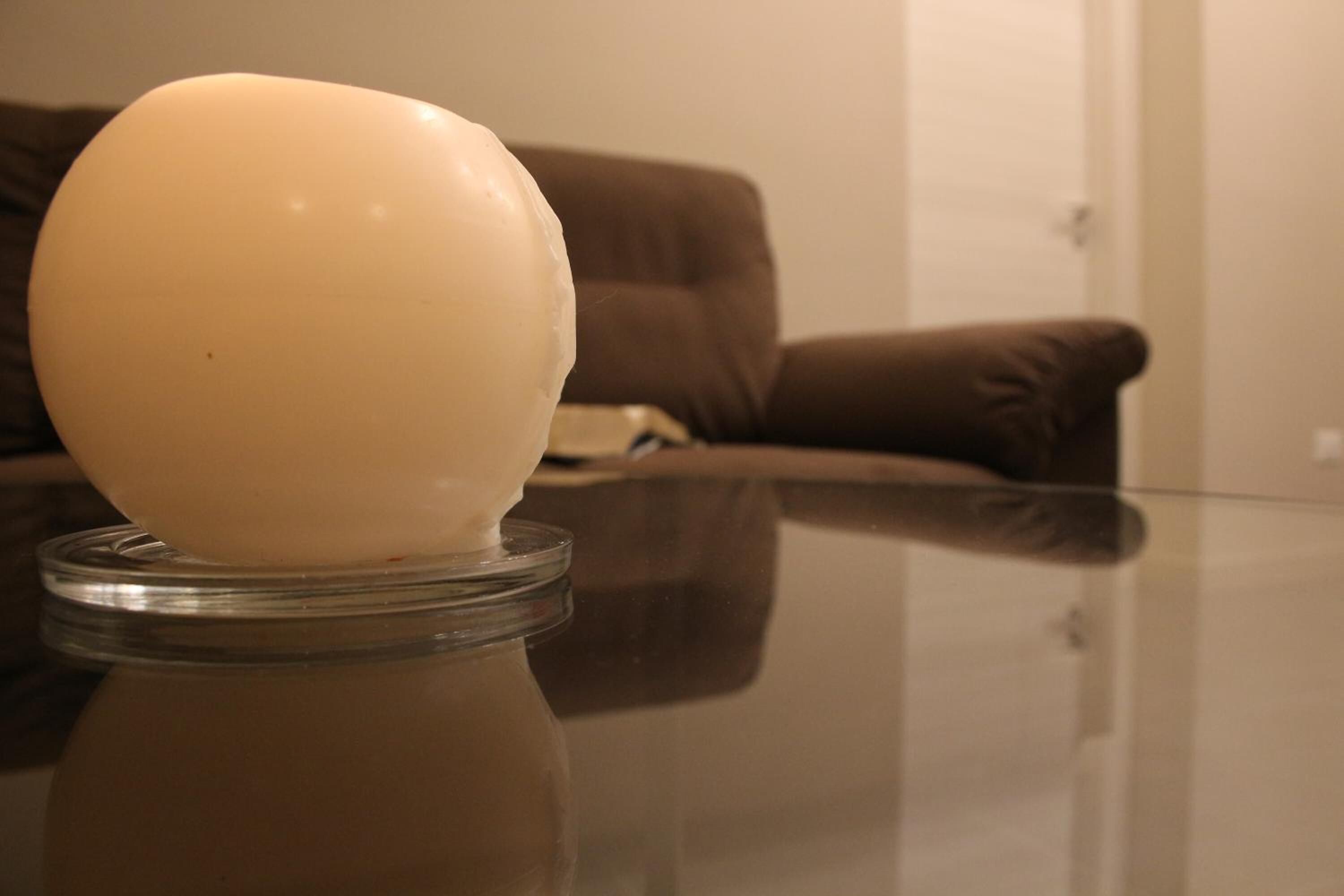 Una mesa de vidrio transparente con un objeto esférico blanco sobre una base de vidrio transparente.