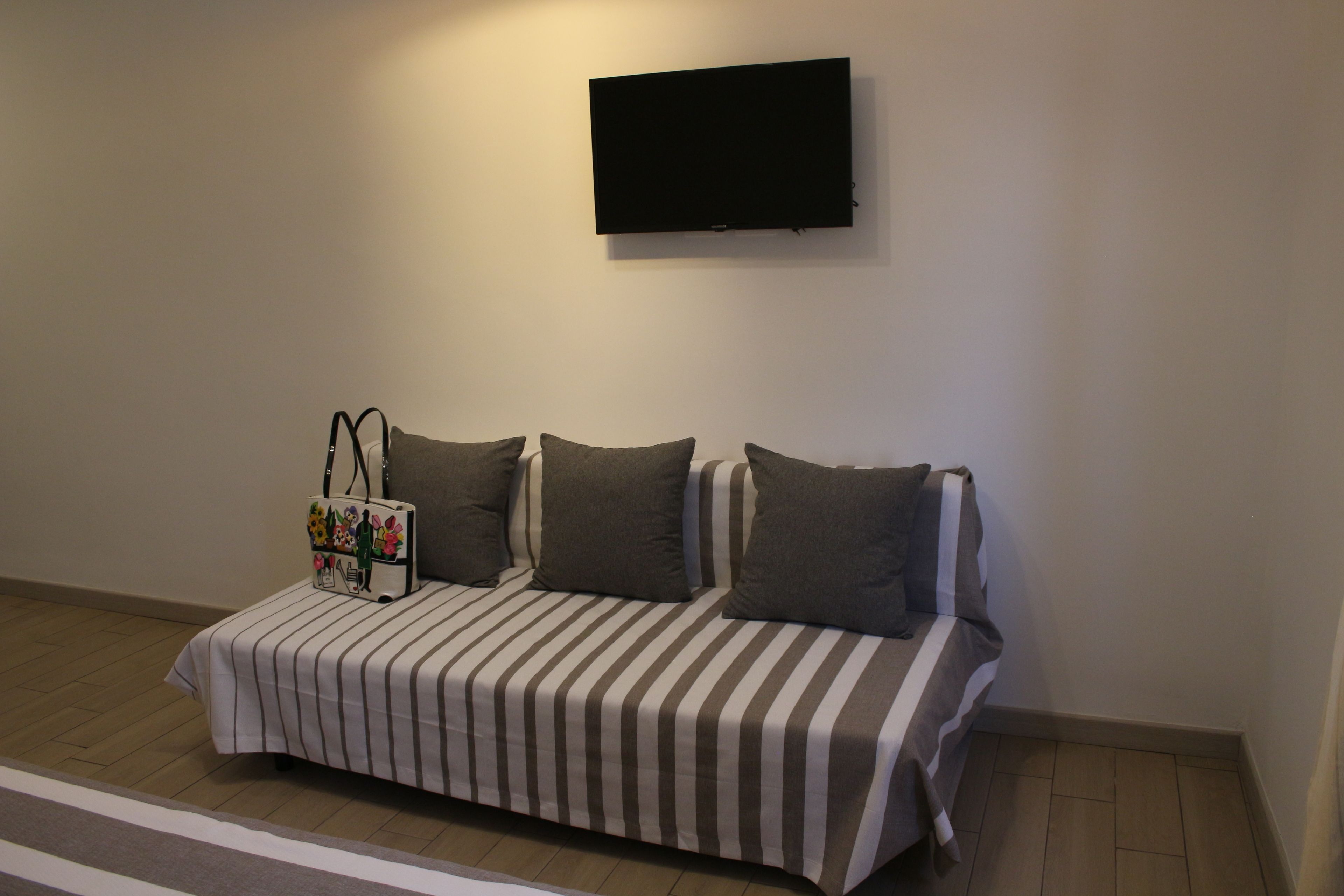 A modern room with a striped sofa, a flat-screen TV mounted on the wall, and a small table with a decorative item.