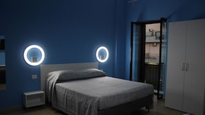 A bedroom with a bed, bedside tables, a wardrobe, and a circular light fixture on the wall.