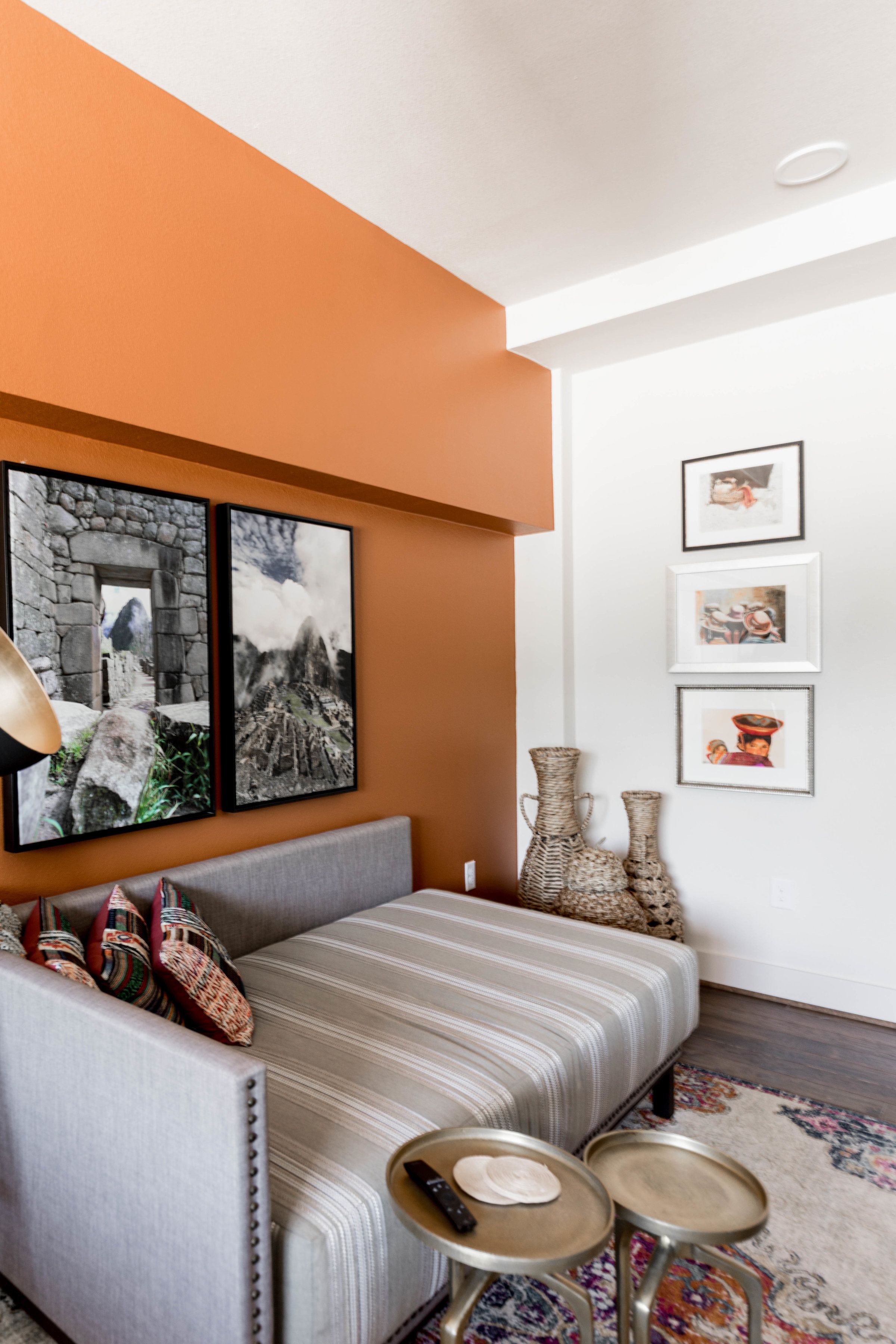 Una sala de estar moderna con un sofá gris, un tapete estampado y una pared con cuadros y jarrones.