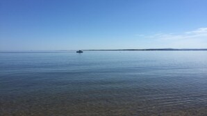 A calm sea with a small boat in the distance and a clear sky. - Tigh Na Mara (Fortrose)