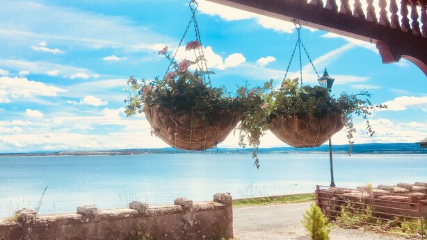 A balcony with a view of a body of water, a hanging flower basket, and a lantern. - Tigh Na Mara (Fortrose)