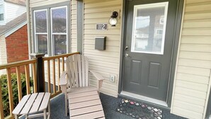 A front porch with a wooden chair and a welcome mat.