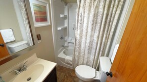 A bathroom with a sink, toilet, and shower. - Escape to our cozy retreat, just a 10-min drive to Greensburg (Youngwood)