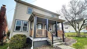 A two-story house with a front porch, a brick chimney, and a small front yard.
