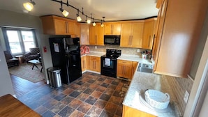 A kitchen with wooden cabinets, a black refrigerator, a microwave, a stove, and a sink.