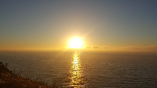 Ein Sonnenuntergang über ruhigem Meer mit klarem Horizont.