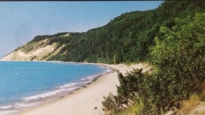 Ein Strand mit sandigem Ufer und einer bewaldeten Klippe.