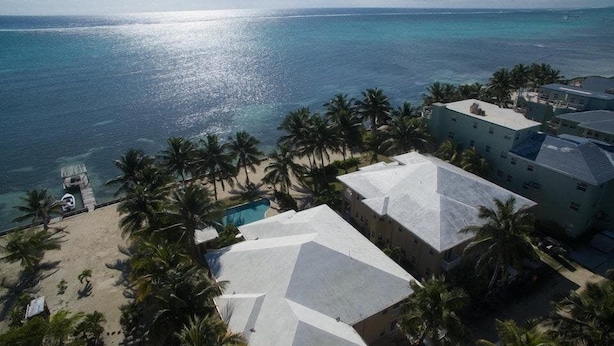 Hotel a la costa amb piscina, envoltat de palmeres i vistes a l'oceà.