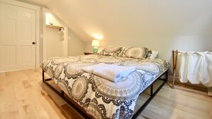 A bedroom with a bed, a nightstand, a lamp, and a door.