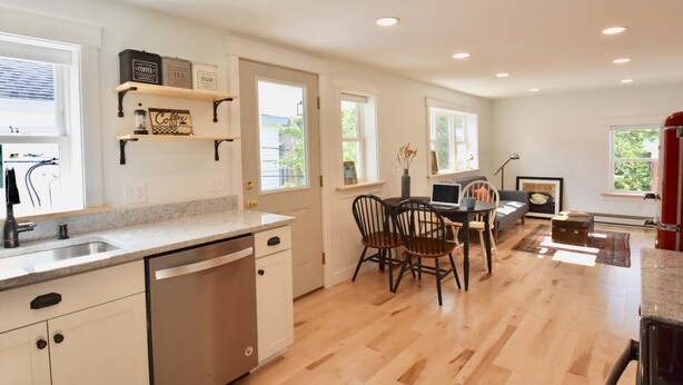 A modern kitchen with a dishwasher, a dining area with chairs, and a red refrigerator.