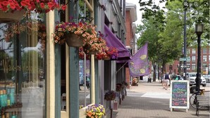 A street with storefronts, including a hair salon and a natural foods shop.