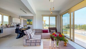A modern living space with a dining area, a sofa, and a balcony with a view. - LIBERTY &  FREEDOM villa, helipad and pools!Perfect for large groups up to 16 ! (Platanias)