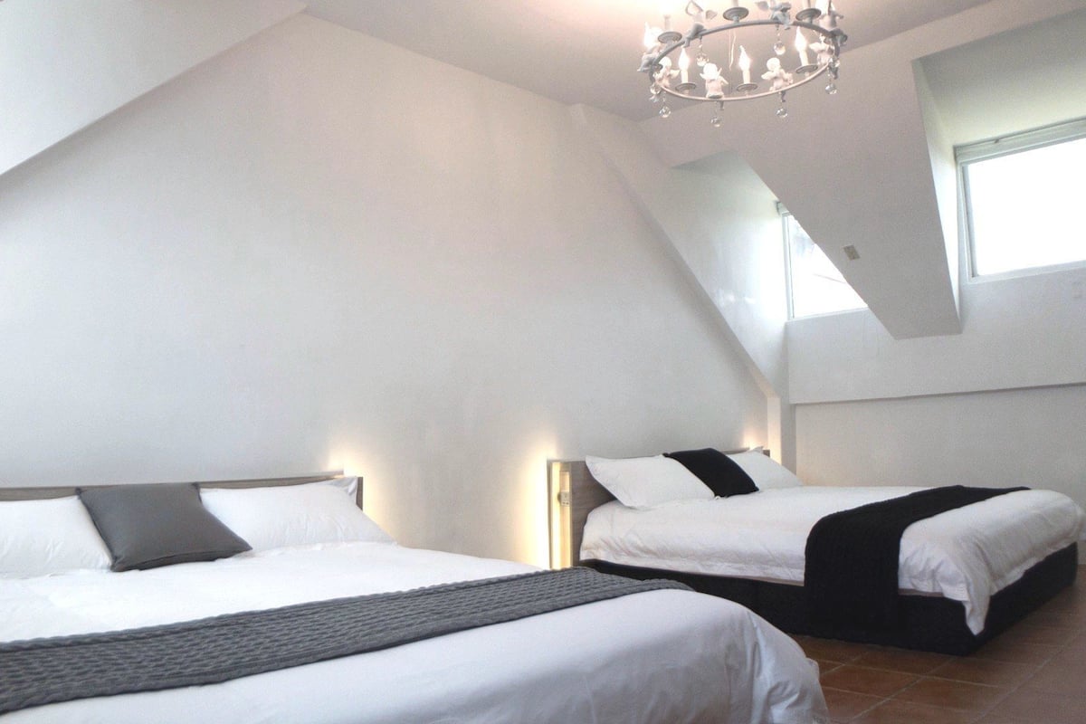 A bedroom with two beds, a chandelier, and a skylight.
