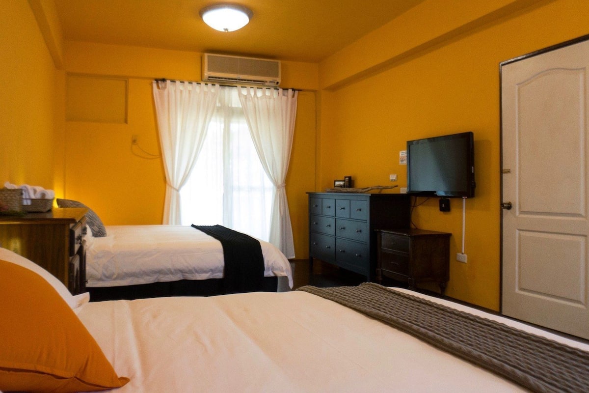 A hotel room with two beds, a television, a wardrobe, and a door.