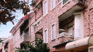 A row of brick buildings with balconies, windows, and a paved street. - AgaPe Plus Home (Hengchun)