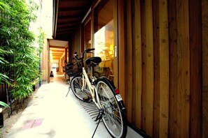 A bicycle parked outside a building with a wooden exterior and a covered walkway.