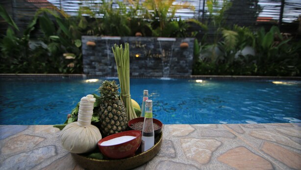 A tray with a bottle, a bowl, and a pineapple by a poolside. - My Unique Angkor Siemreap (Siem Reap)