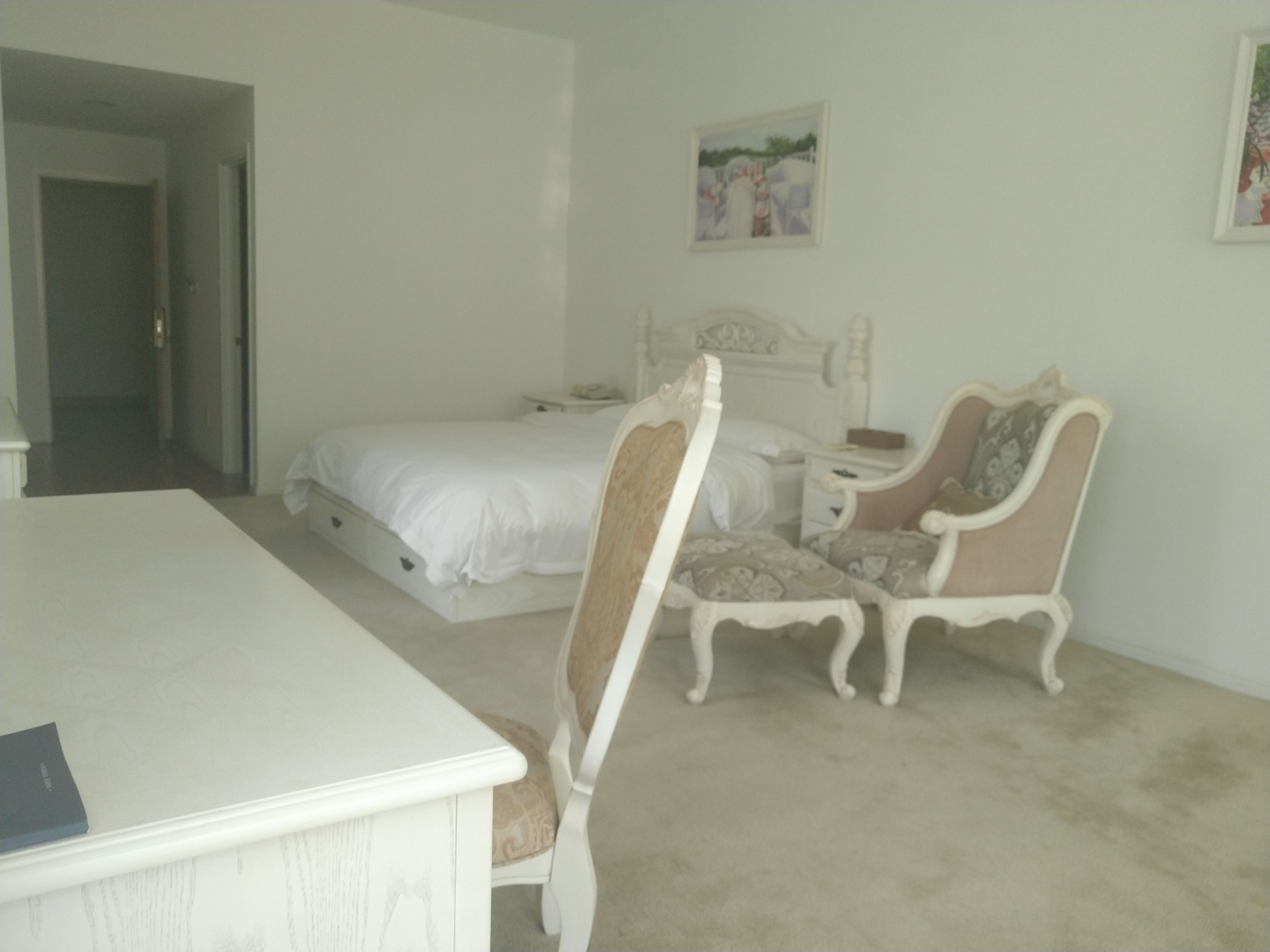 A bedroom with a bed, a desk, a chair, and a dresser.
