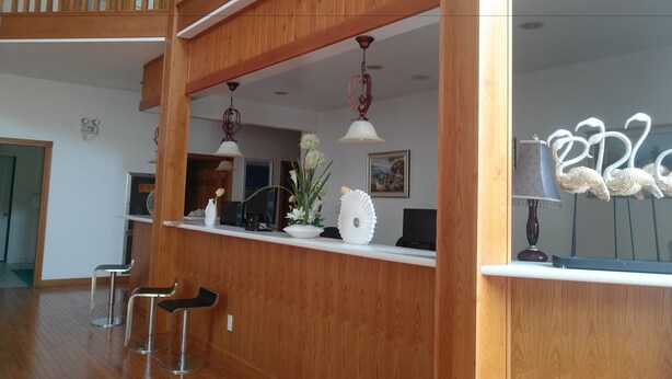 A wooden reception desk with two bar stools, a ceiling fan, and a decorative metal sign. - Solar food&drink campsite (Dezhou)