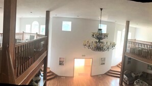 A spacious interior with wooden floors, a grand staircase, and a chandelier. - Solar food&drink campsite (Dezhou)