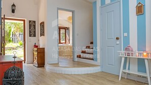 Ein geräumiges Zimmer mit Holzboden, einer weißen Tür und einer blauen Wand. Ein kleiner Tisch mit Lampe und Stuhl steht dort.