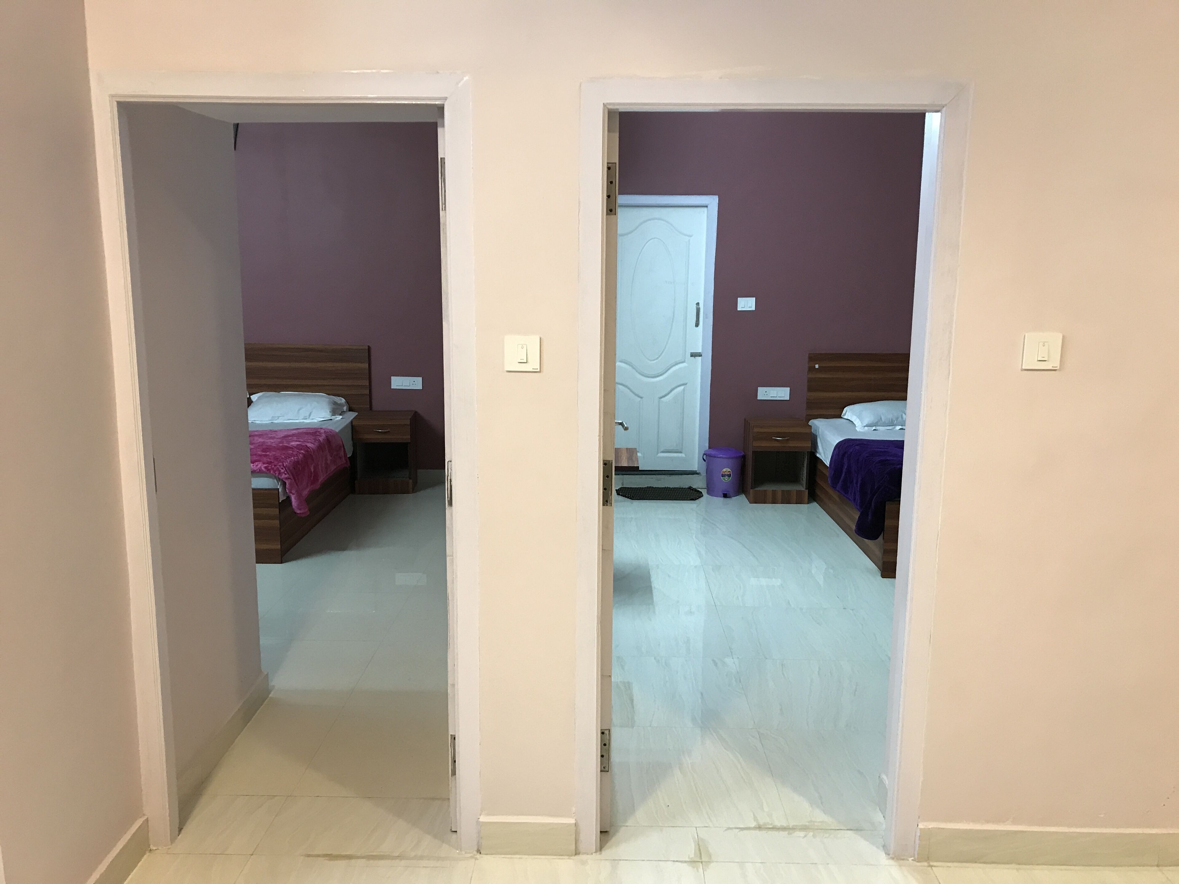A hallway leading to two bedrooms, each with a bed, nightstand, and a door.