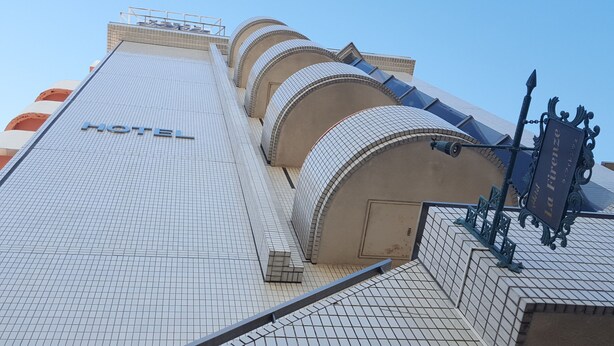 A hotel with a tiled facade, a prominent 'HOTEL' sign, and a sign reading 'La Firenze'. - BUSINESS HOTEL La Firenze (Tokyo)