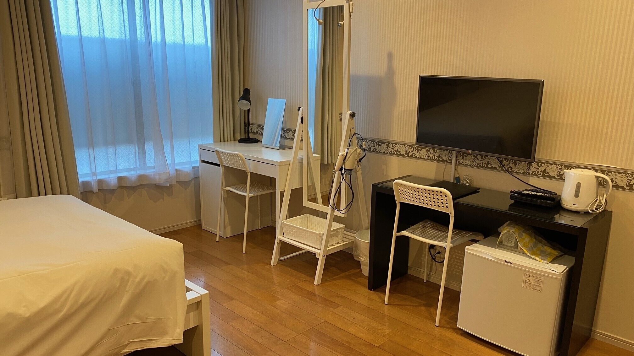 A hotel room with a bed, desk, chair, television, and a small refrigerator.
