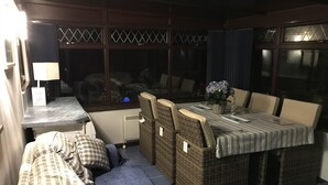 A cozy outdoor seating area with a table and chairs, a sofa, and a small table with a lamp. - The Batch, 5* Self Catering Bungalow, St Merryn Padstow (St Merryn)
