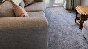 A living room with a grey sofa, a wooden coffee table, and plaid curtains. - The Batch, 5* Self Catering Bungalow, St Merryn Padstow (St Merryn)