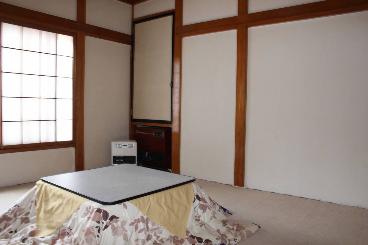 Ein traditioneller japanischer Raum mit Tatami-Bodenbelag, einem niedrigen Tisch und einer Schiebetür.