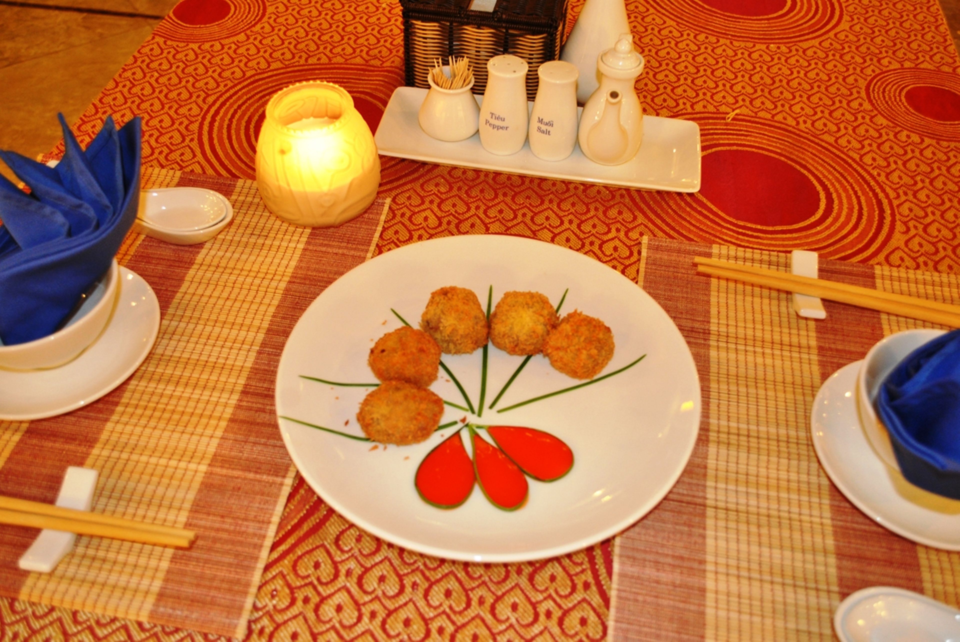 A dining table with a plate of food, chopsticks, and salt and pepper shakers.