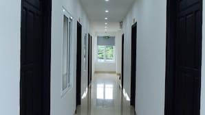 Um corredor comprido e estreito com portas pretas e placas numeradas indicando os números dos quartos.